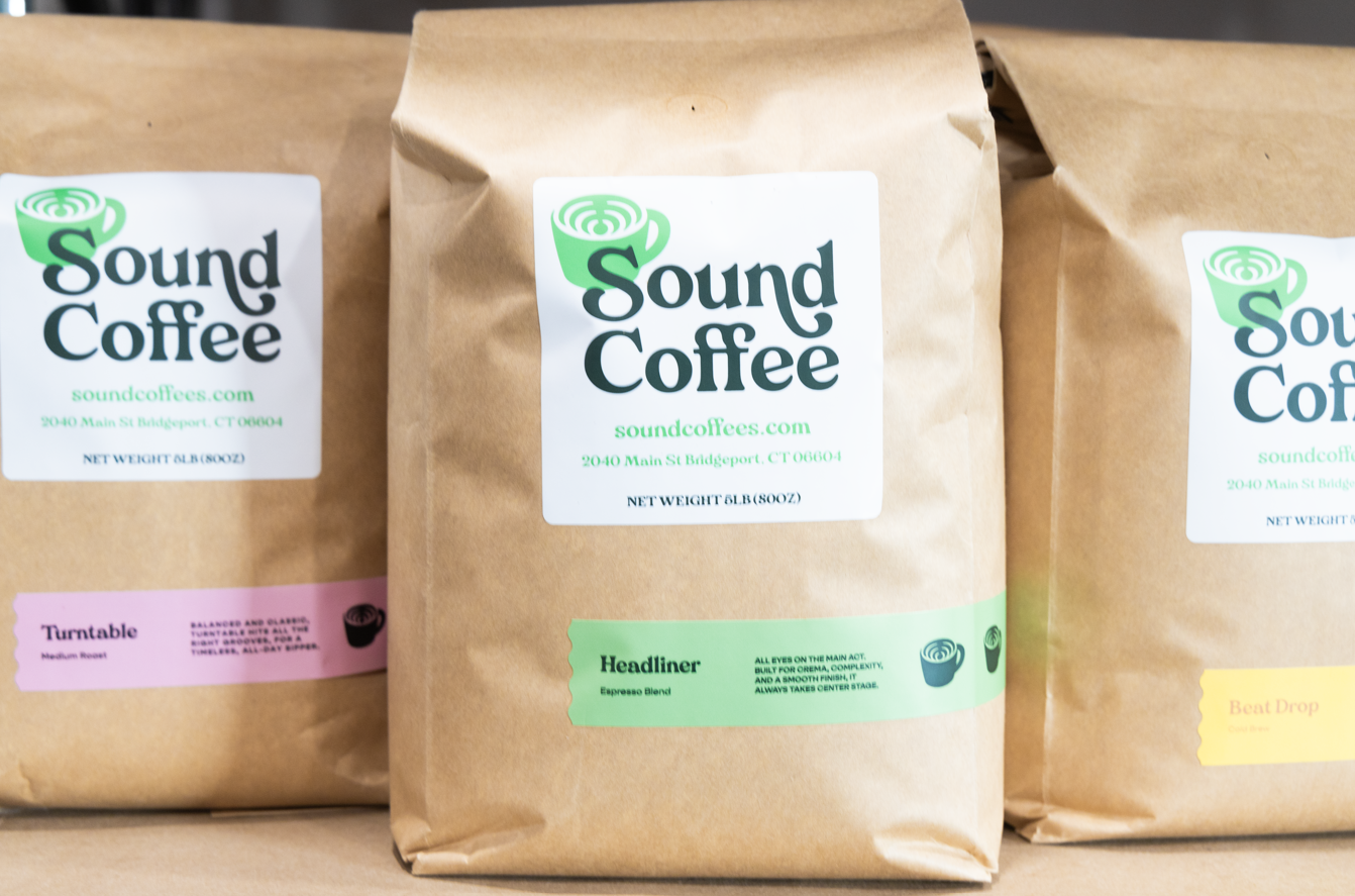 Three 5lb brown paper bags of Sound Coffee beans arranged side by side, with the center bag labeled 'Headliner' in green and the others partially visible in pink and yellow labels.