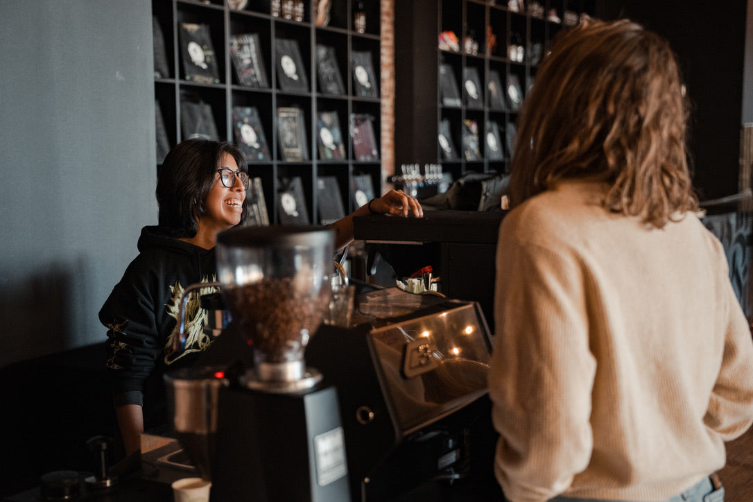 A barista is happily taking an order of the customer in front of the counter