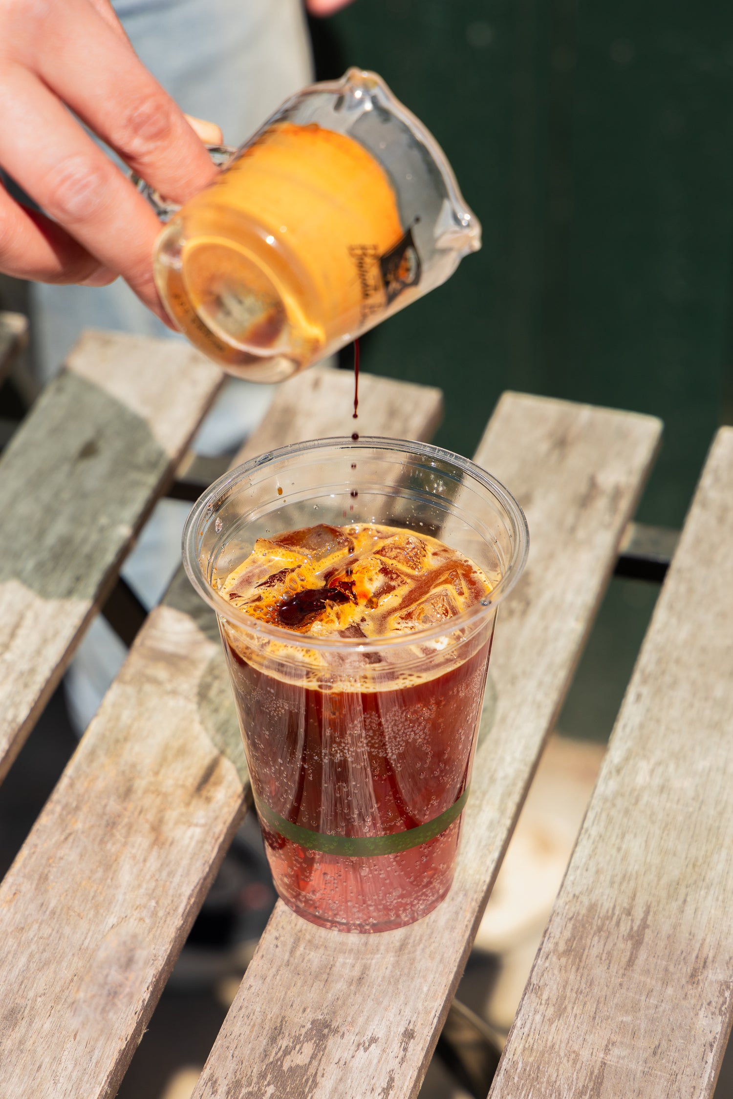 Espresso shot being poured to a drink in a clear plastic cup