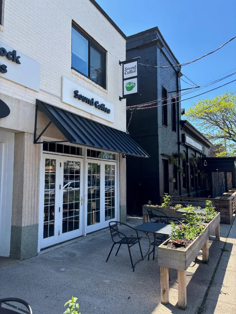 Outdoor seating area in front of a building with 'Sound Coffee' sign.