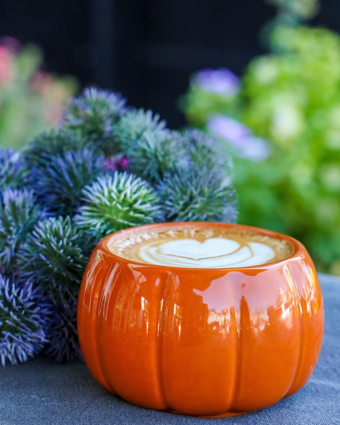 Pumpkin Spice Latte in a pumpkin cup and a plant on the background